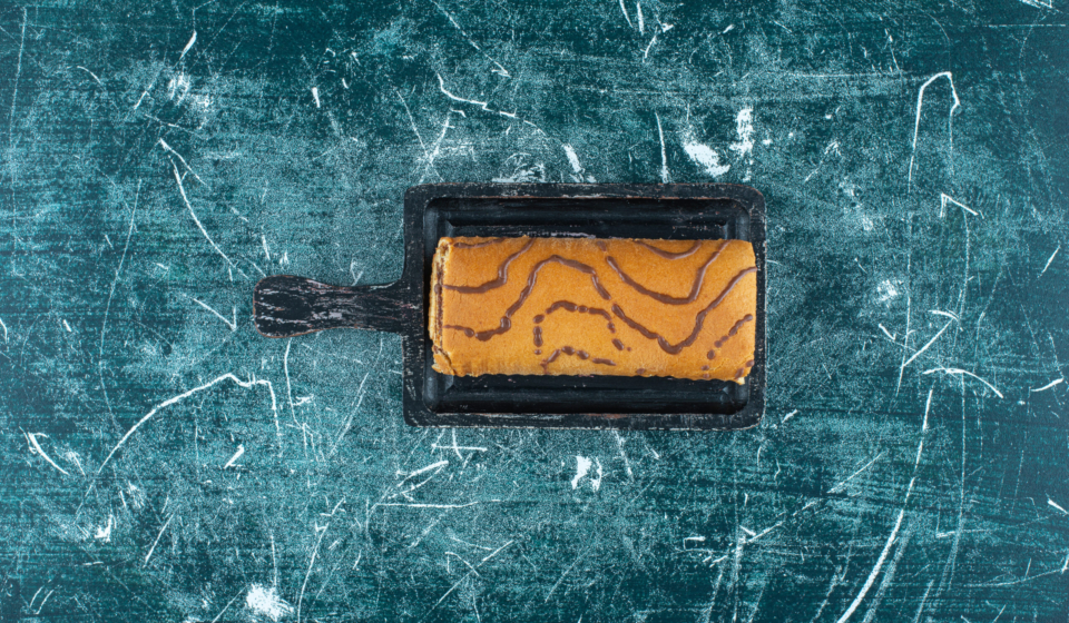 Roll cake on a board , on the blue background. High quality photo
