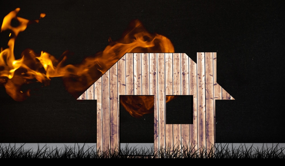 composite of burning house graphic on black grass
