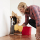 Worried woman mopping up water from a burst pipe with sponge