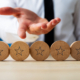 Hand of a businessman presenting five wooden cut circles with stars on them in conceptual image of luxury and wealth.