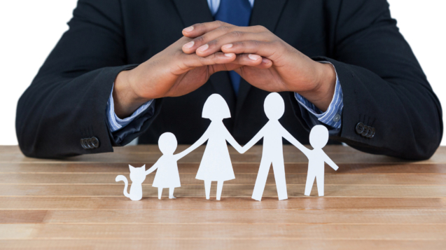 Mid section of businessman protecting paper cut out family, house and car with hands
