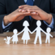 Mid section of businessman protecting paper cut out family, house and car with hands