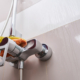 Cropped photo of hand in rubber glove wiping chrome faucet with microfiber cloth