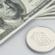 Litecoin coin and a pile of US dollar banknotes. Blockchain money versus fiat money concept